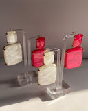 Marbled geometric statement earrings in Pearl White and Fuchsia Pink with gold-tone trim.