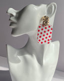 White acrylic polka dot statement earrings with gold-tone textured studs available in red and black variations.