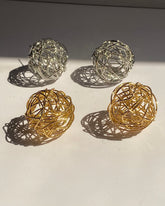 Interwoven orb statement earrings in gold and silver finishes.