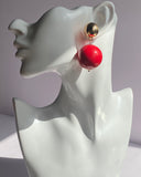 Gold ball drop statement earrings with glossy red and black sphere variations and polished gold-tone studs.