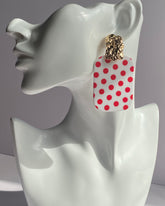 White acrylic polka dot statement earrings with gold-tone textured studs available in red and black variations.