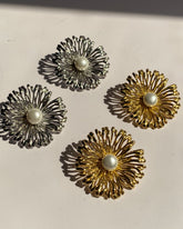 Pearl center sunburst stainless steel stud earrings available in gold and silver finishes.