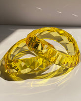 Transparent yellow faceted crystal statement bangle bracelet with reflective geometric detailing.