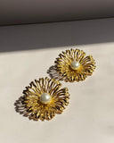 Pearl center sunburst stainless steel stud earrings available in gold and silver finishes.