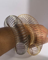 Gold and silver expandable wire cuff bracelets worn on wrist showing open statement style