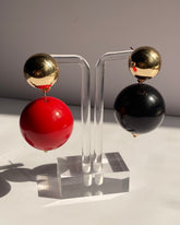 Gold ball drop statement earrings with glossy red and black sphere variations and polished gold-tone studs.