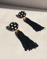 Black and white polka dot tassel statement earrings with gold trim and long black fringe.