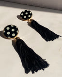 Black and white polka dot tassel statement earrings with gold trim and long black fringe.