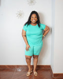 Plus size woman wearing a mint green matching biker short set with a crew neck short sleeve top and fitted biker shorts.