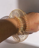 Gold adjustable coil bracelet expanded into bold statement cuff on wrist