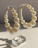 Elegant faux pearl hoop earrings featuring graduated pearl sizing for a timeless statement look.