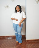 Model wearing white stretch plus size top with light wash jeans.