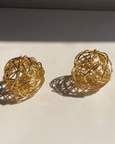Interwoven orb statement earrings in gold and silver finishes.