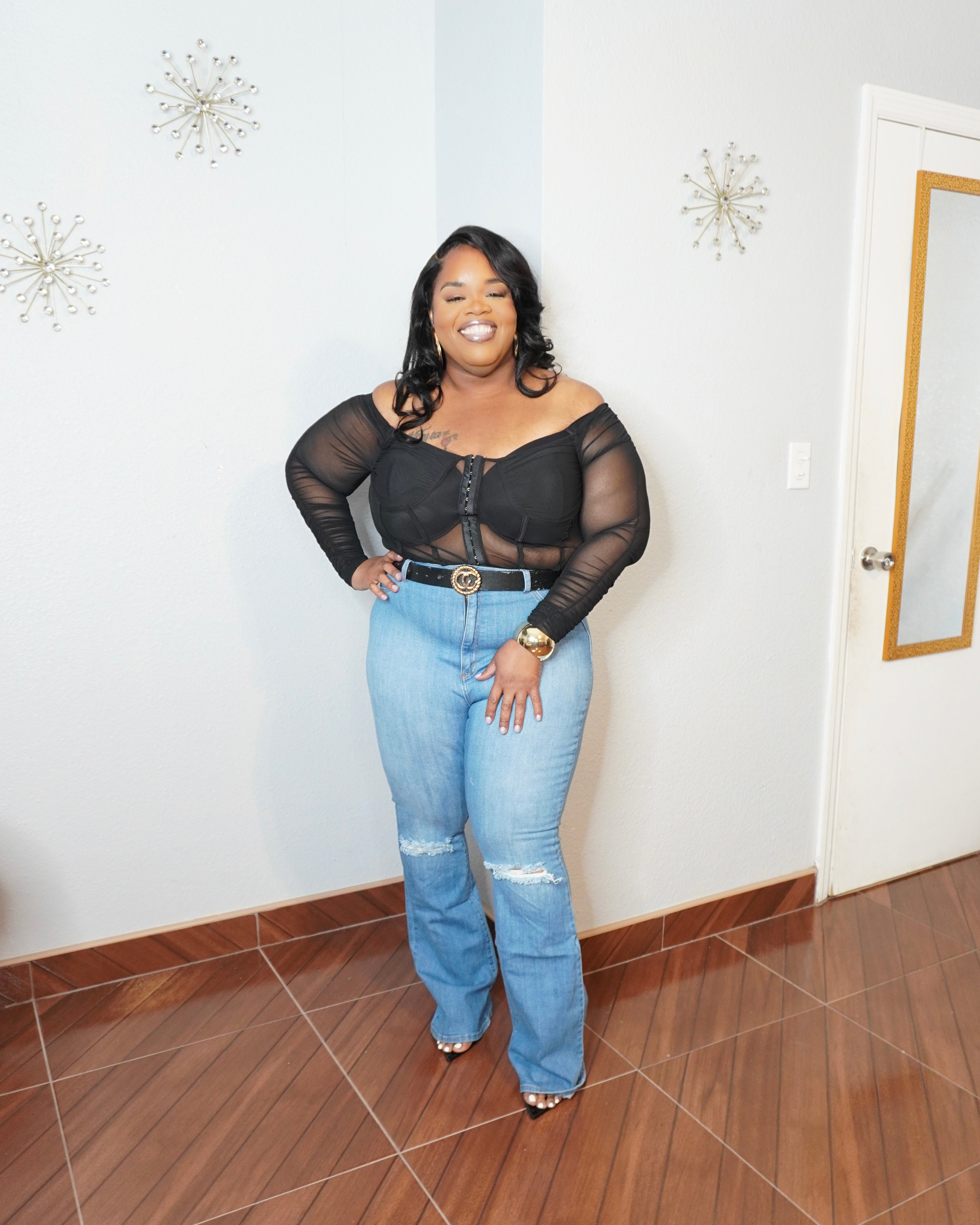 Full body view of plus size woman wearing black mesh top with ripped jeans