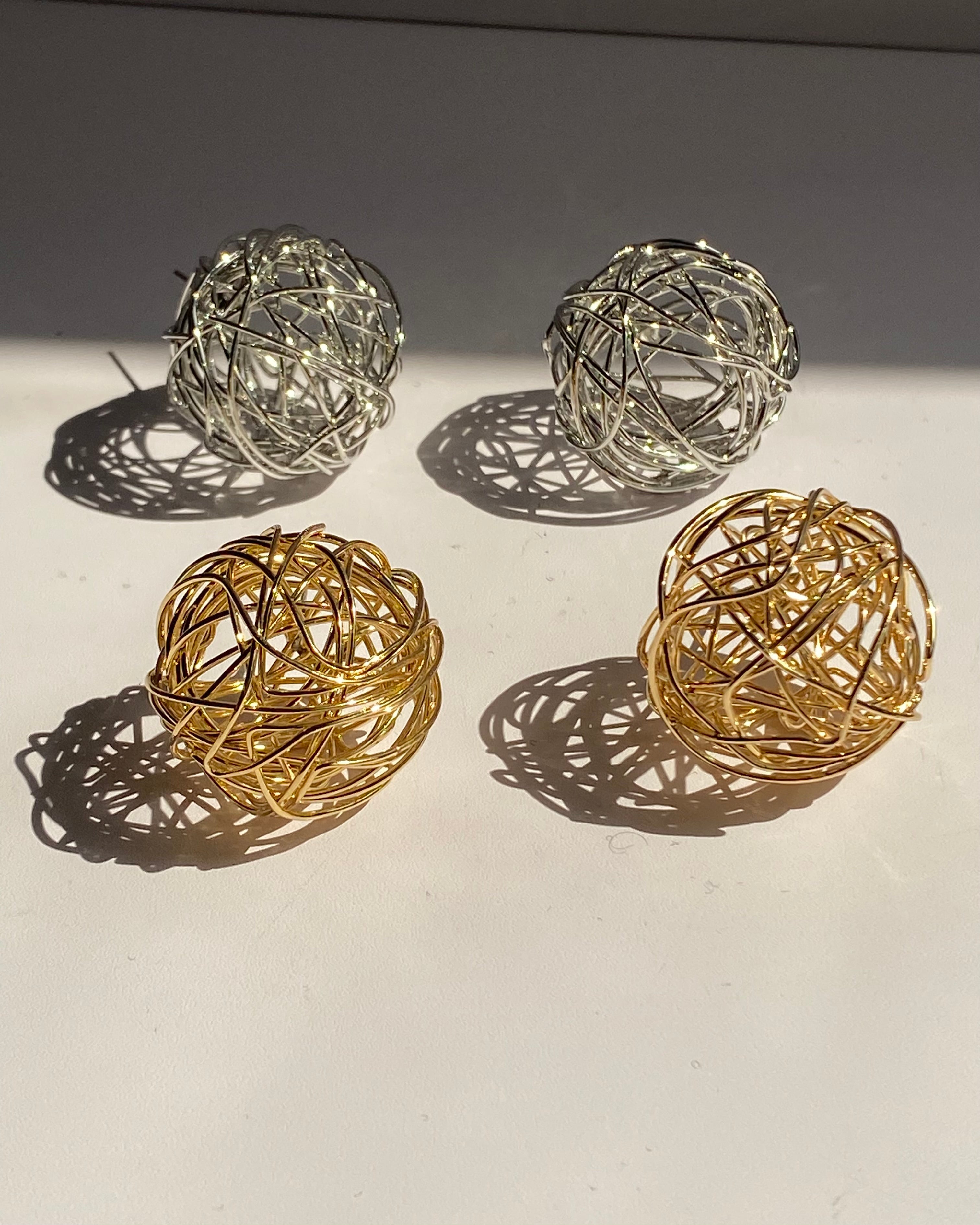 Interwoven orb statement earrings in gold and silver finishes.