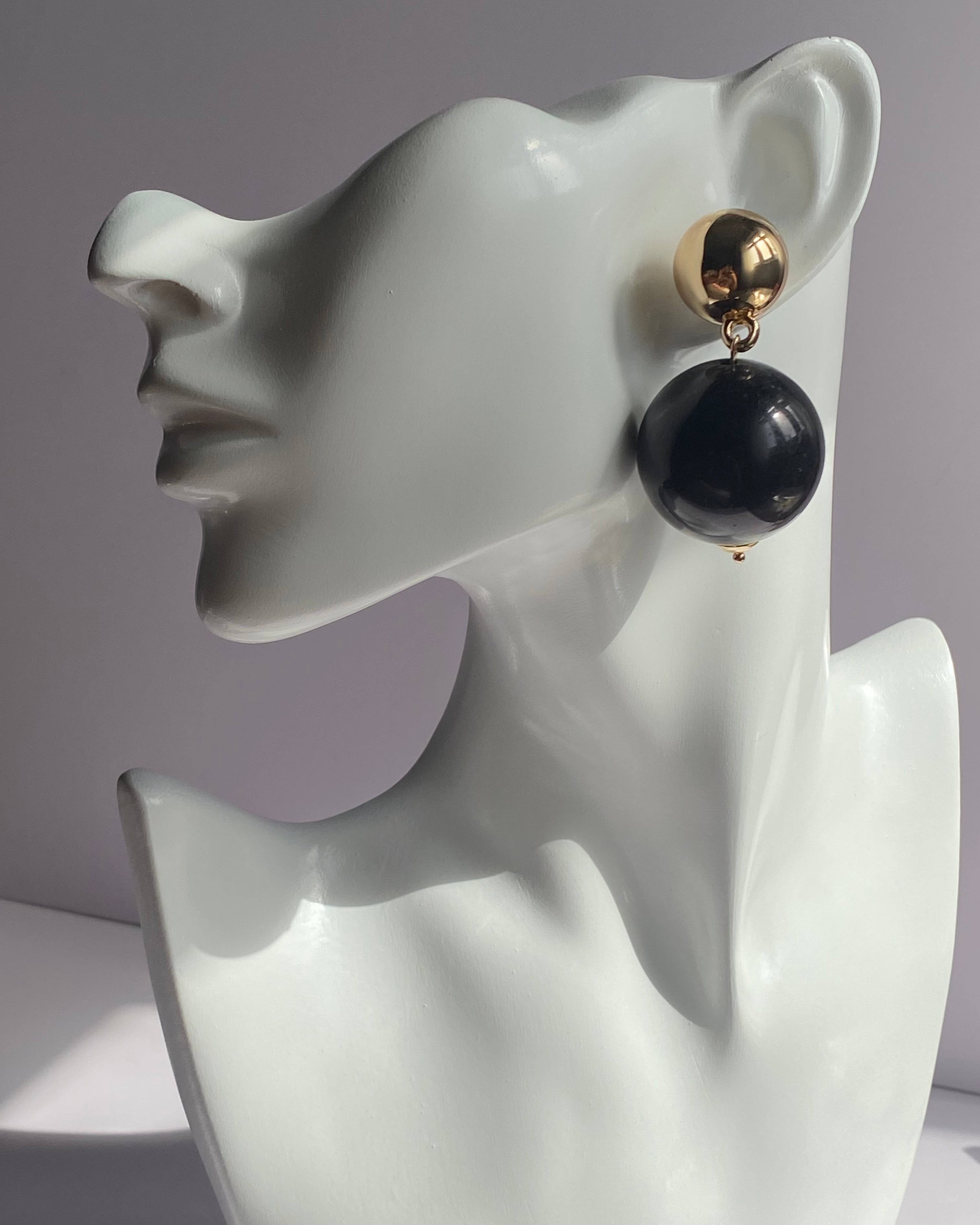 Gold ball drop statement earrings with glossy red and black sphere variations and polished gold-tone studs.