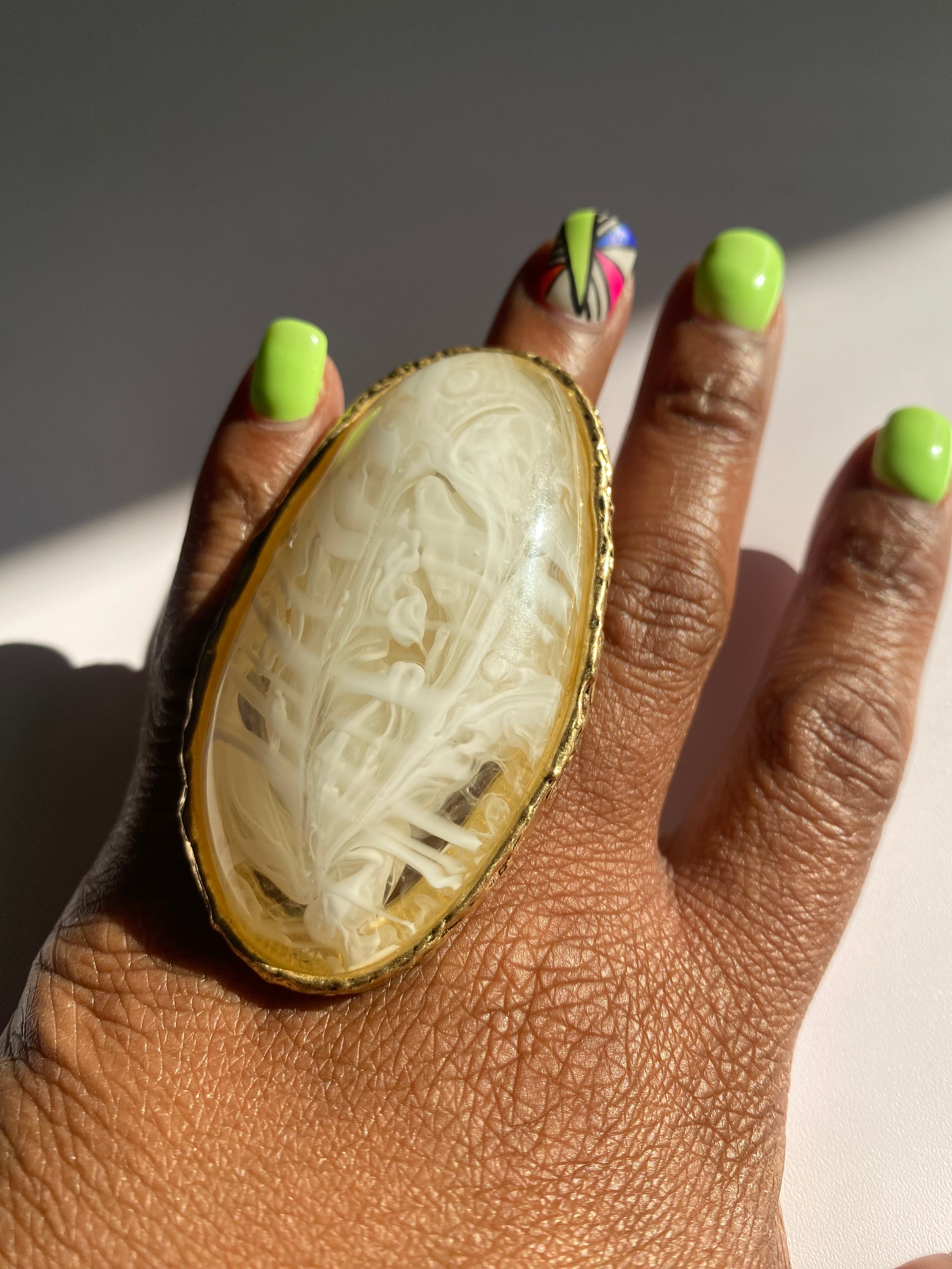 Ivory marbled resin cocktail ring featuring a textured gold-tone setting.