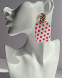 White acrylic polka dot statement earrings with gold-tone textured studs available in red and black variations.
