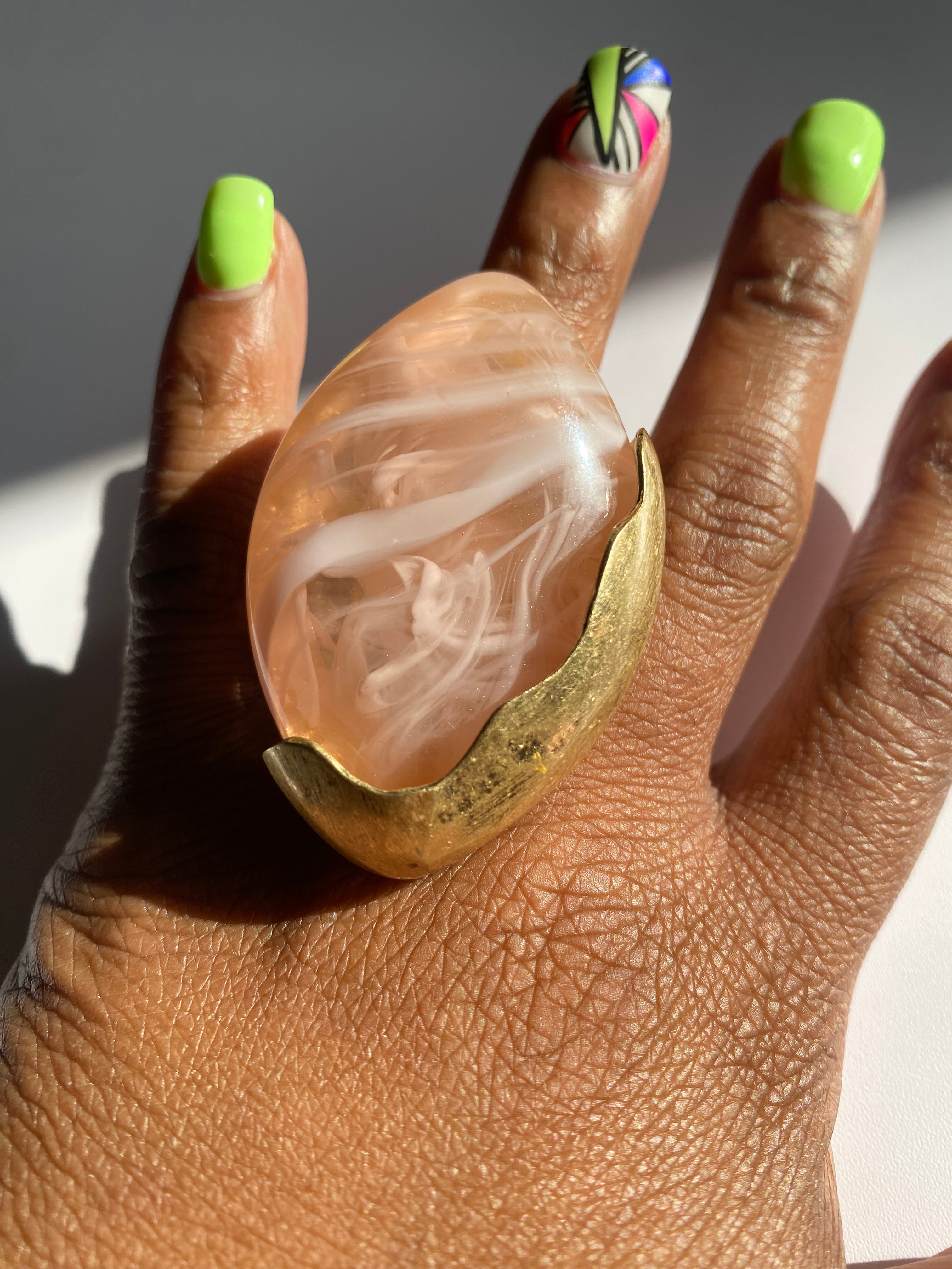 Blush marbled resin statement ring with adjustable gold-tone band.
