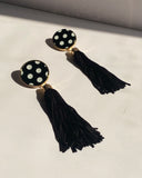 Black and white polka dot tassel statement earrings with gold trim and long black fringe.