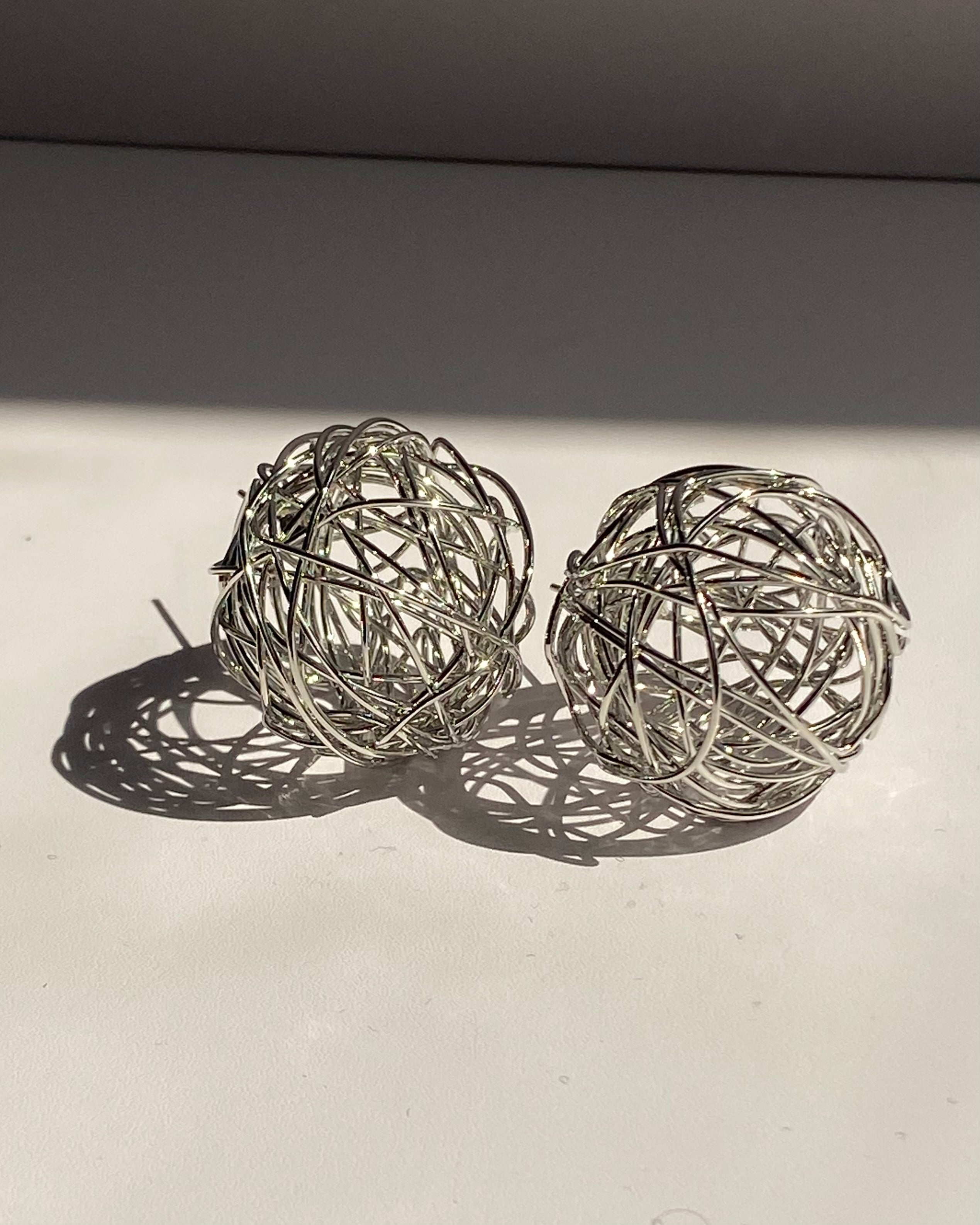 Interwoven orb statement earrings in gold and silver finishes.