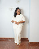 Plus size model wearing an oatmeal scuba knit matching set with a curved hem top and wide leg pants.