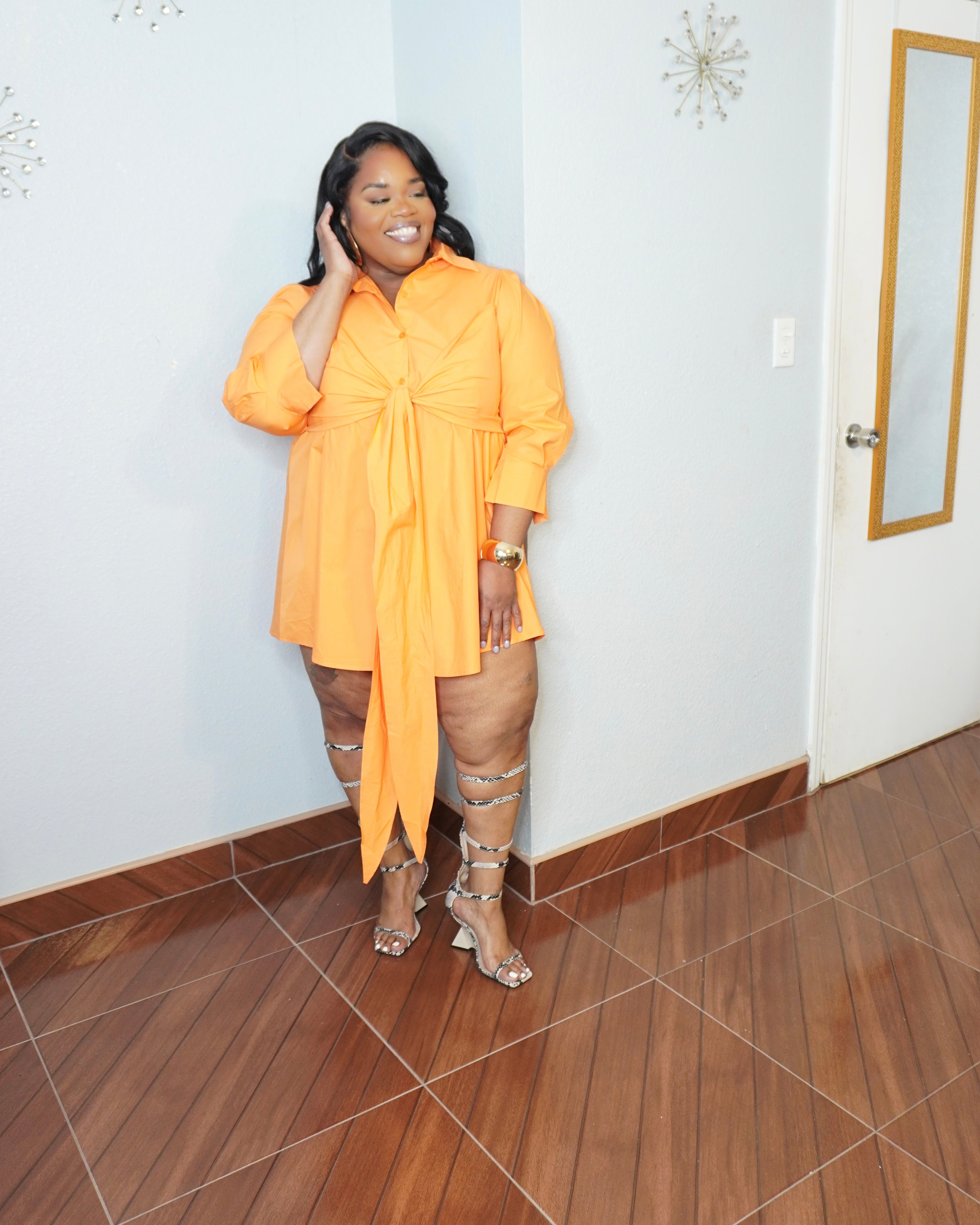 Front smiling pose of plus size woman wearing orange mini shirt dress