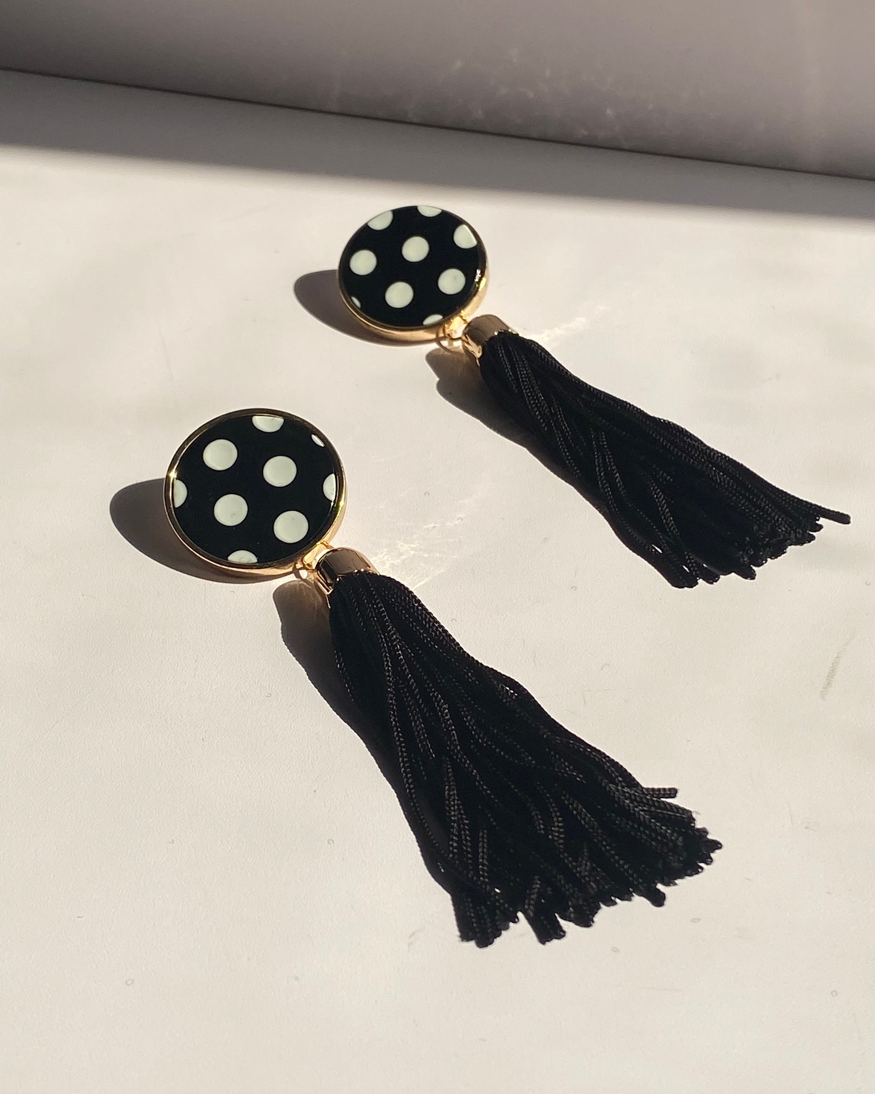 Black and white polka dot tassel statement earrings with gold trim and long black fringe.