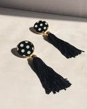 Black and white polka dot tassel statement earrings with gold trim and long black fringe.