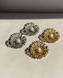 Pearl center sunburst stainless steel stud earrings available in gold and silver finishes.