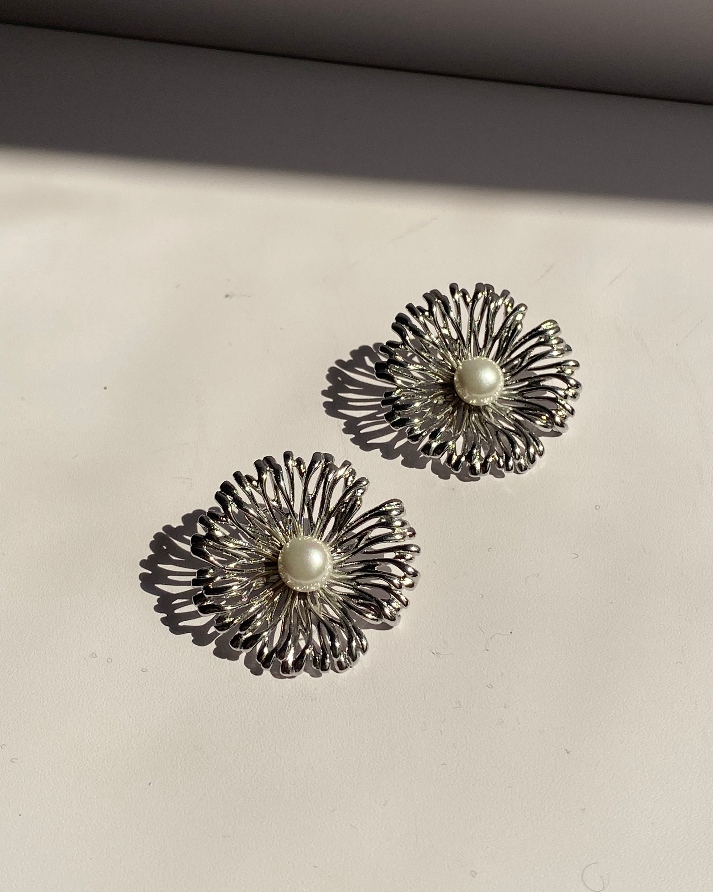 Pearl center sunburst stainless steel stud earrings available in gold and silver finishes.