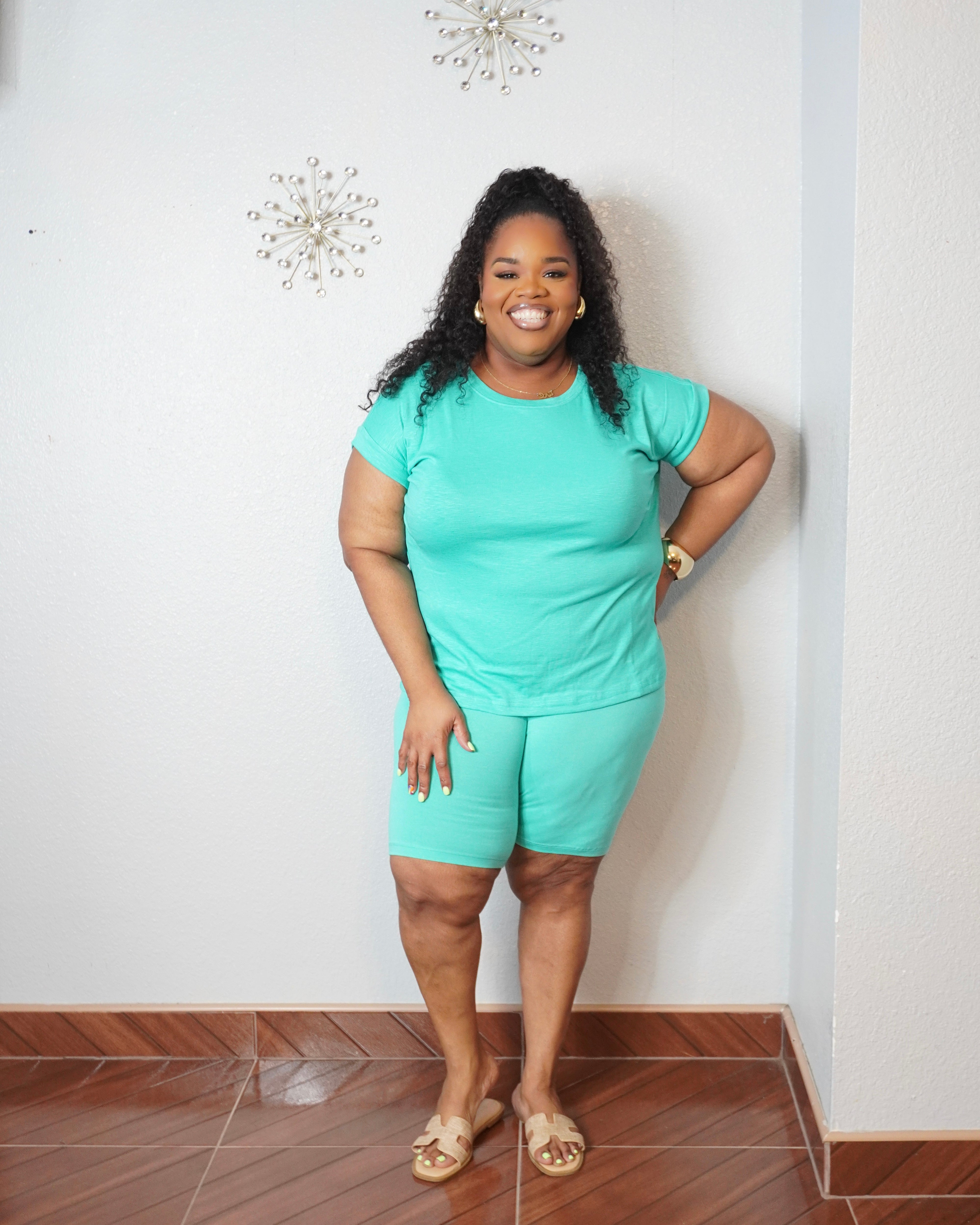 Plus size woman wearing a mint green matching biker short set with a crew neck short sleeve top and fitted biker shorts.