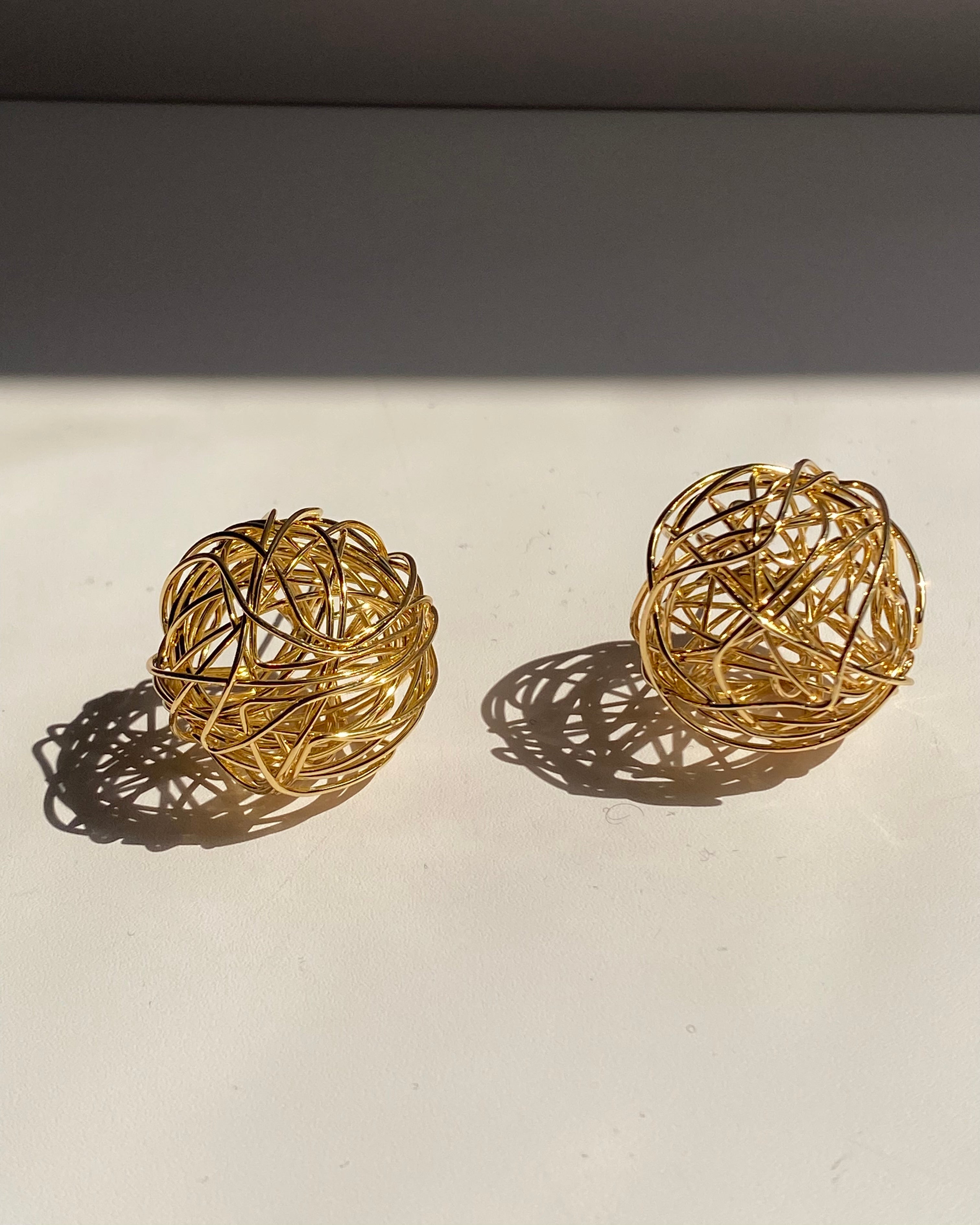 Interwoven orb statement earrings in gold and silver finishes.