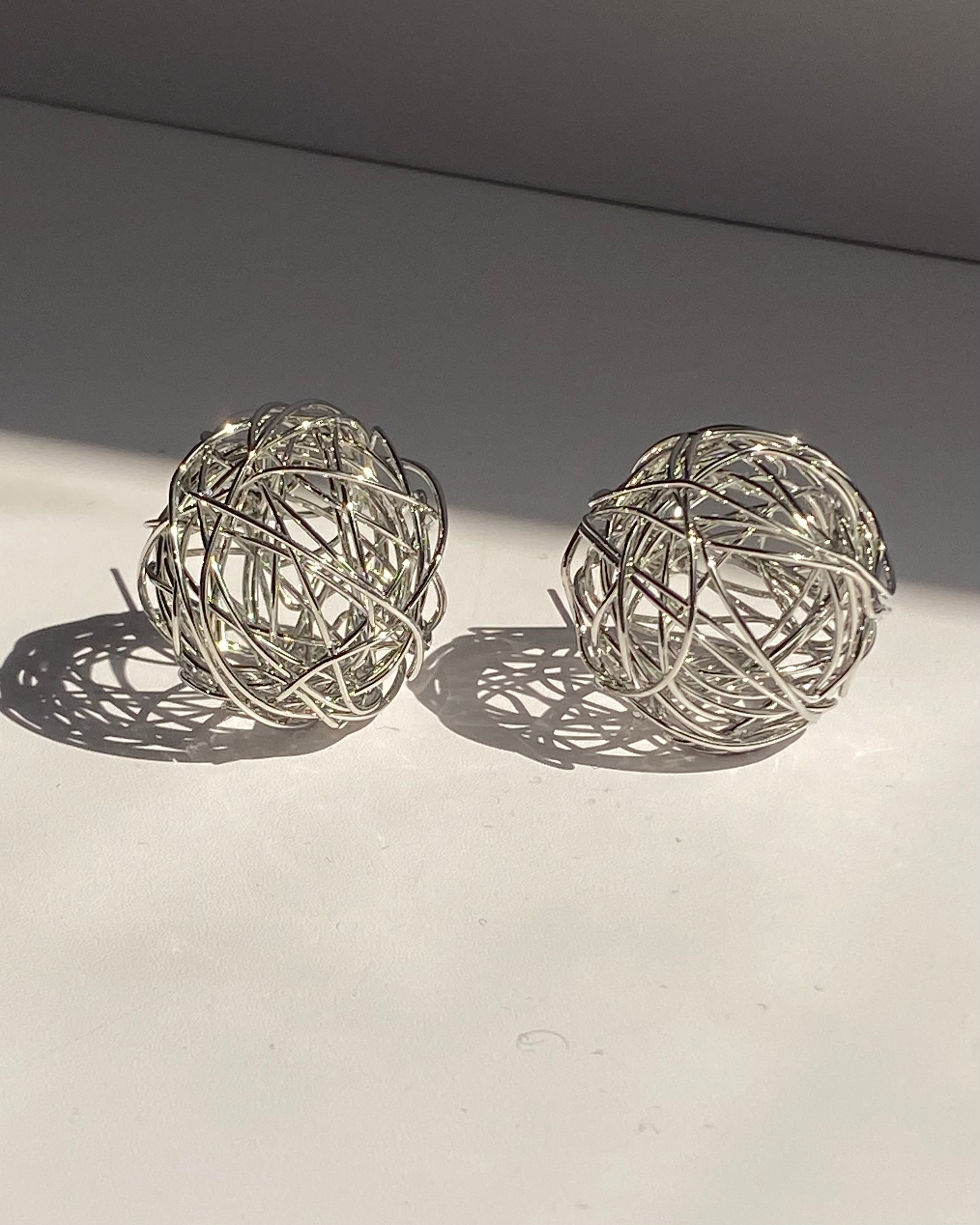 Interwoven orb statement earrings in gold and silver finishes.
