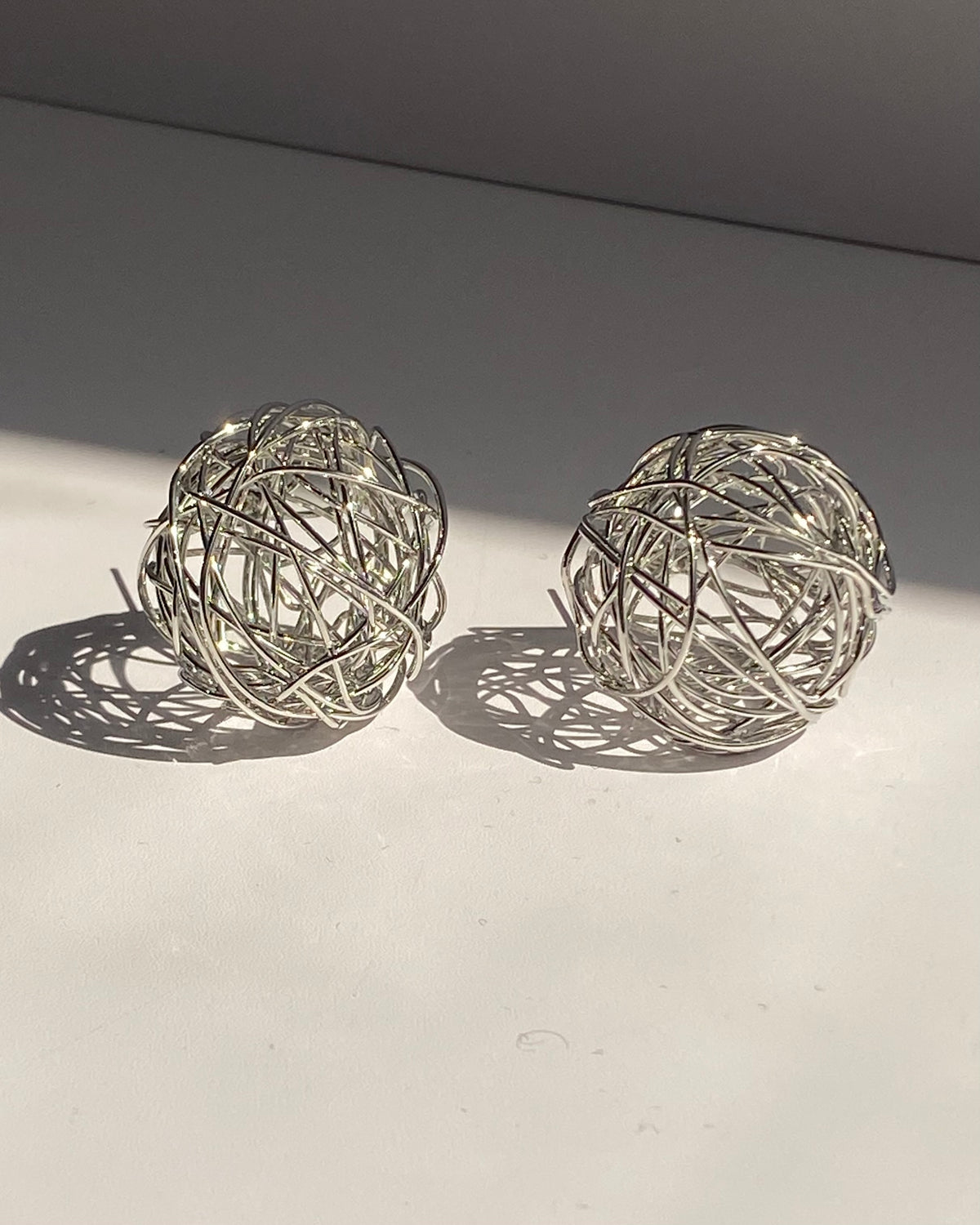 Interwoven orb statement earrings in gold and silver finishes.