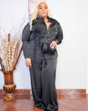 Front view of plus size black two piece pant set with button down top and 3D flower detail